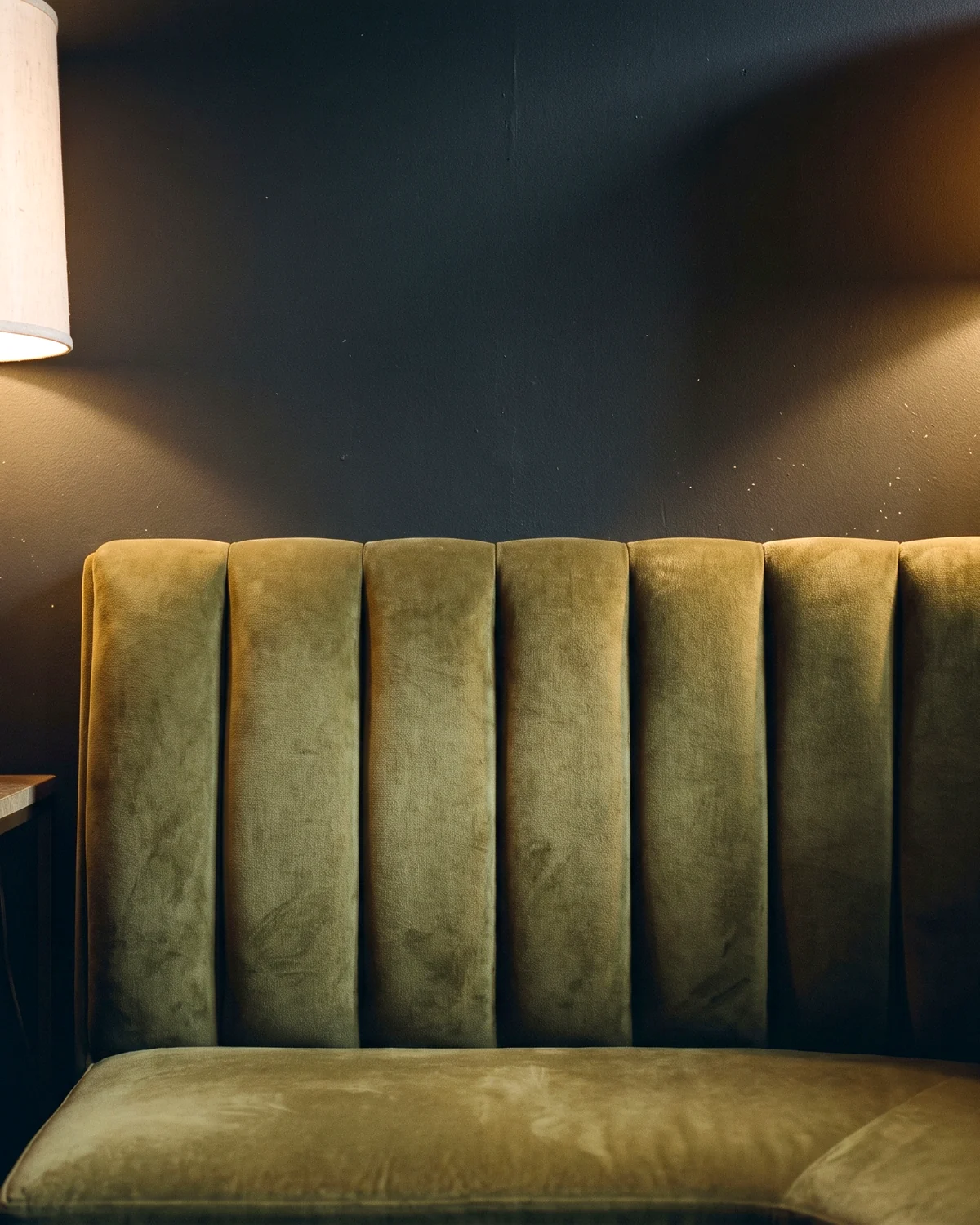 An olive velvet channel-back booth